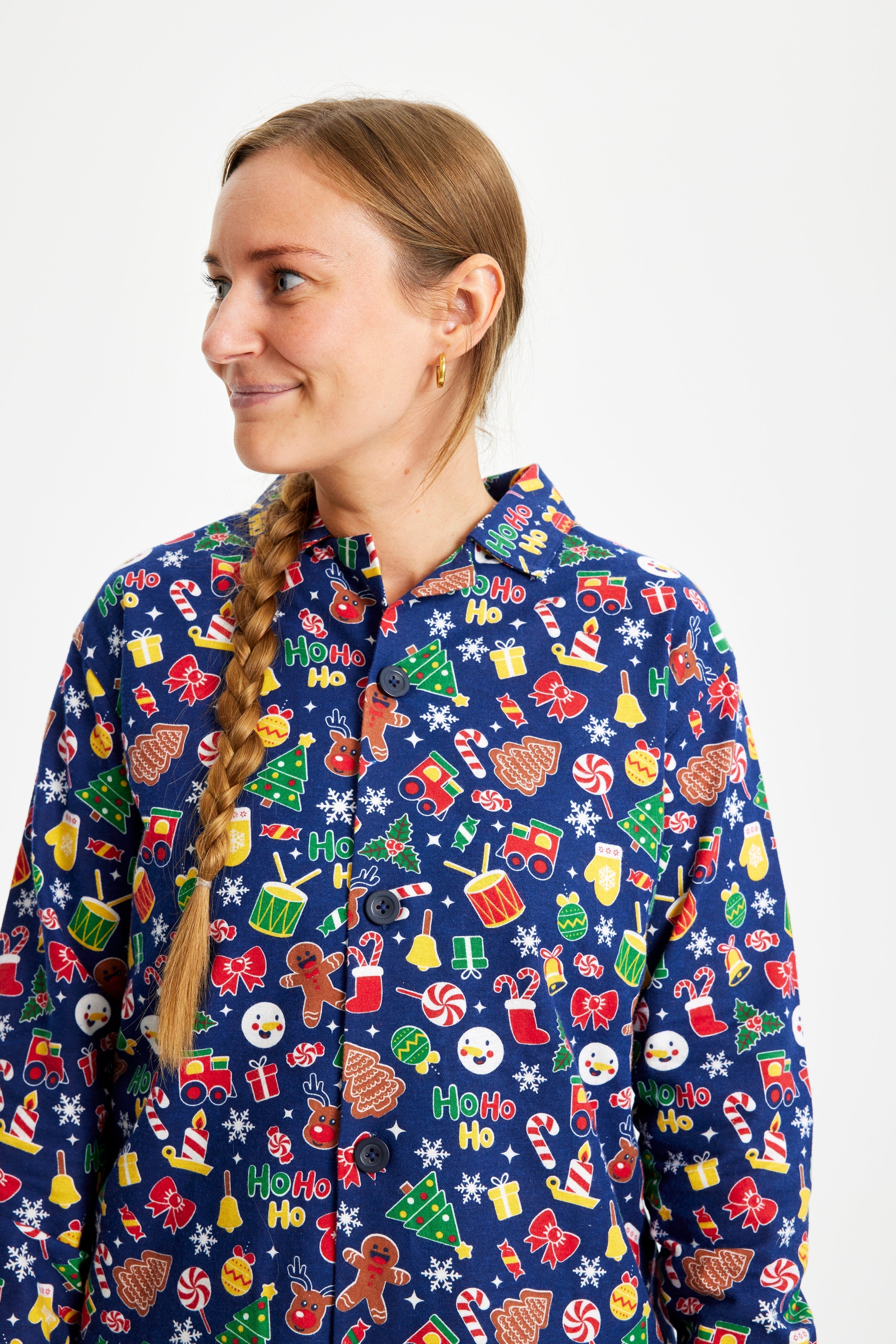 Une femme regardant sur le côté portant un pyjama de Noël bleu avec un imprimé de Noël.